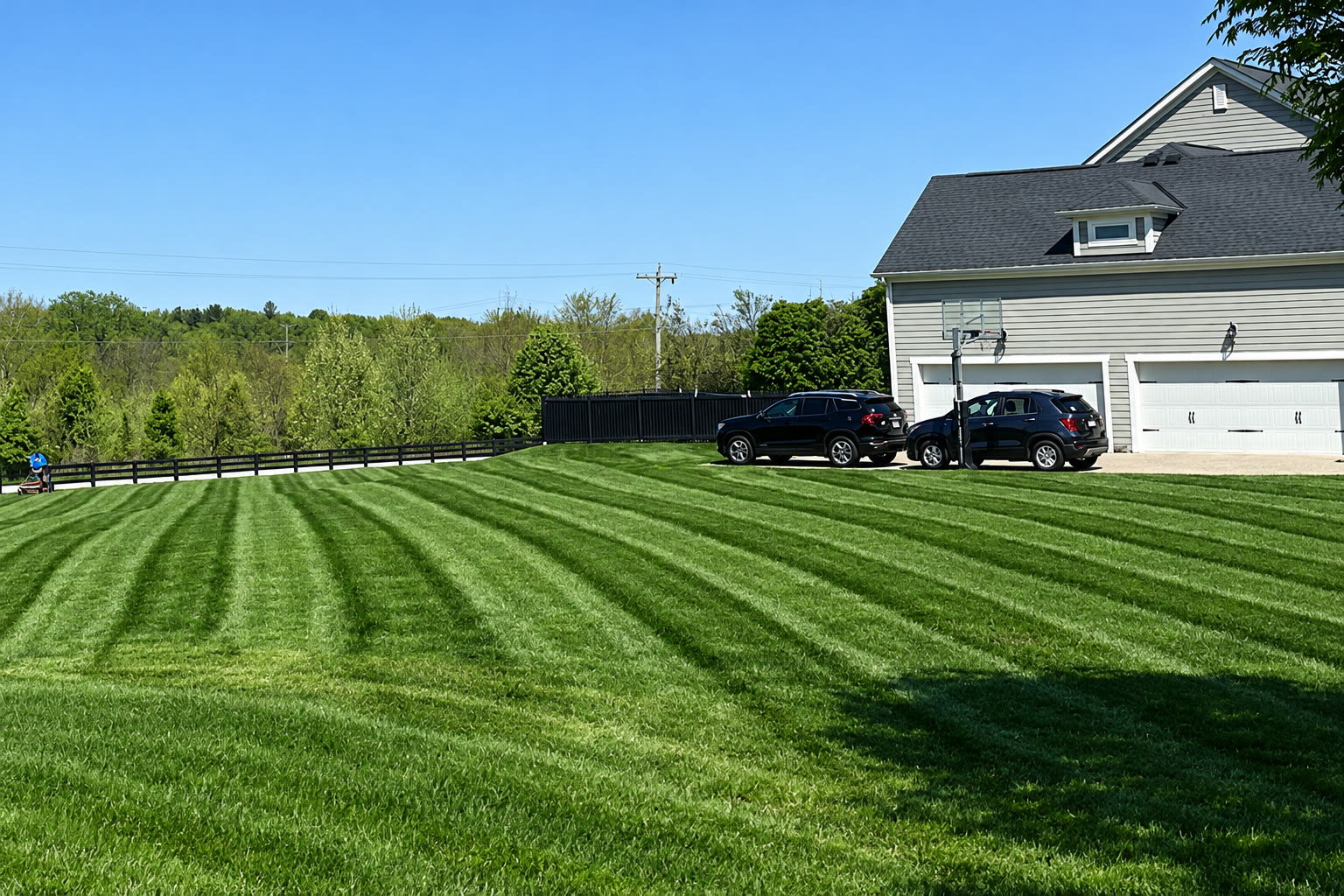 Striped lawn beside a garage and tree line