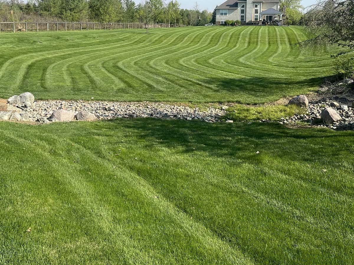 Thick lawn with curved mowing stripes along a stone border
